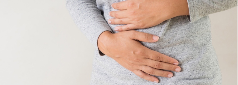 woman holds abdomen wondering how to prevent recurrent hernia after undergoing hernia repair surgery in Florida 