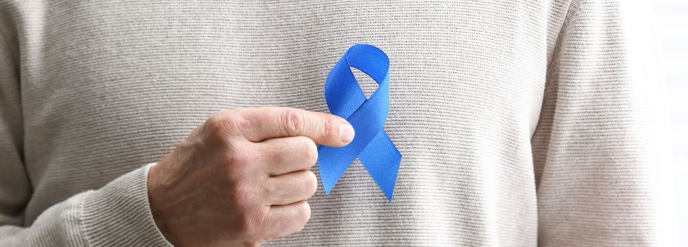 Colorectal cancer survivor holds blue ribbon celebrating new cancer research success and hope for the future 