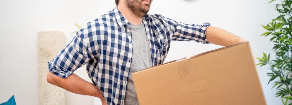 Man in pain as he lifts heavy box after hernia surgery