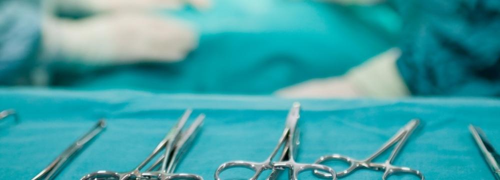 surgical instruments lying on tray with surgeons performing hernia surgery in the background