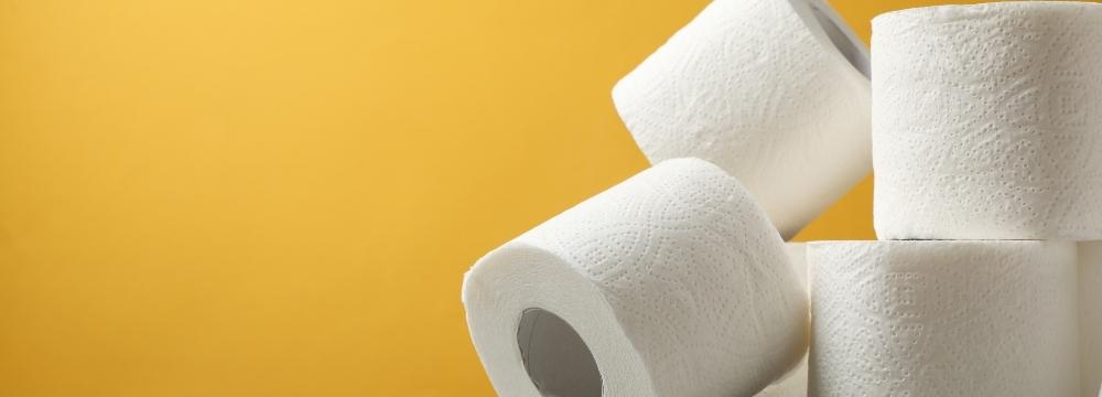 Toilet paper stacked in front of yellow background