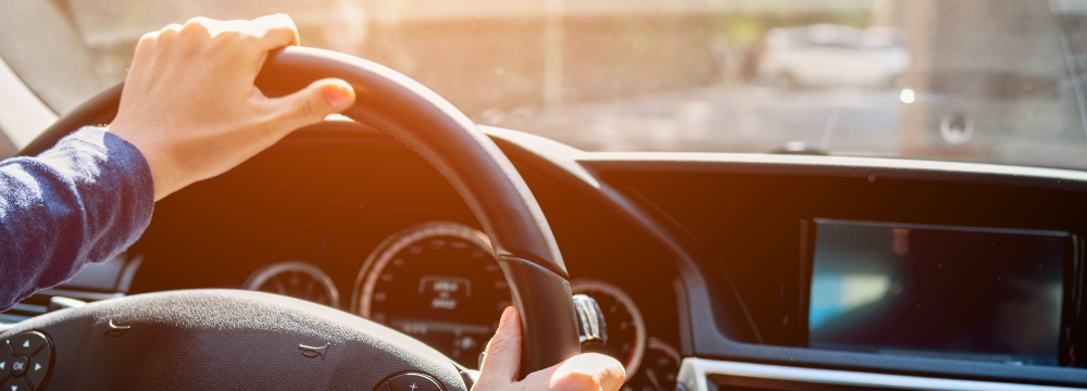 person's hands on the steering wheel driving